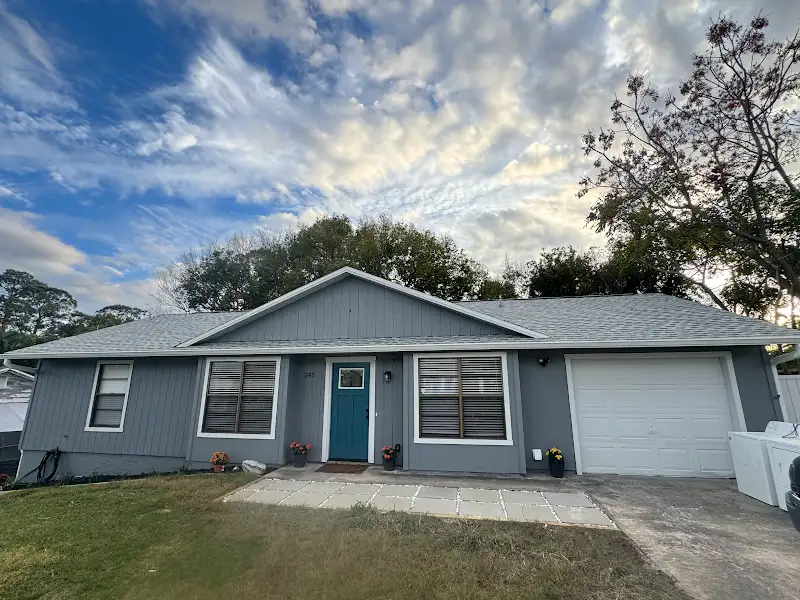 Gray house with teal front door renovated by JM Home Industries