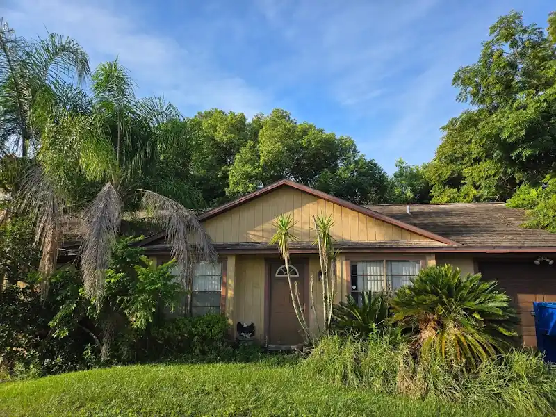 Home exterior with tropical landscaping by JM Home Industries