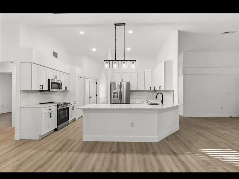 Modern white kitchen renovation with island and pendant lights by JM Home Industries
