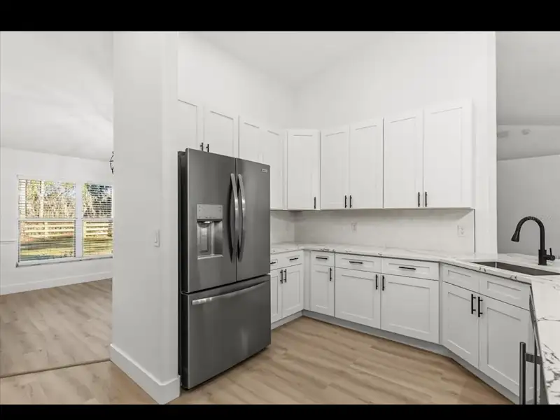 Kitchen with white cabinets and French door fridge by JM Home Industries