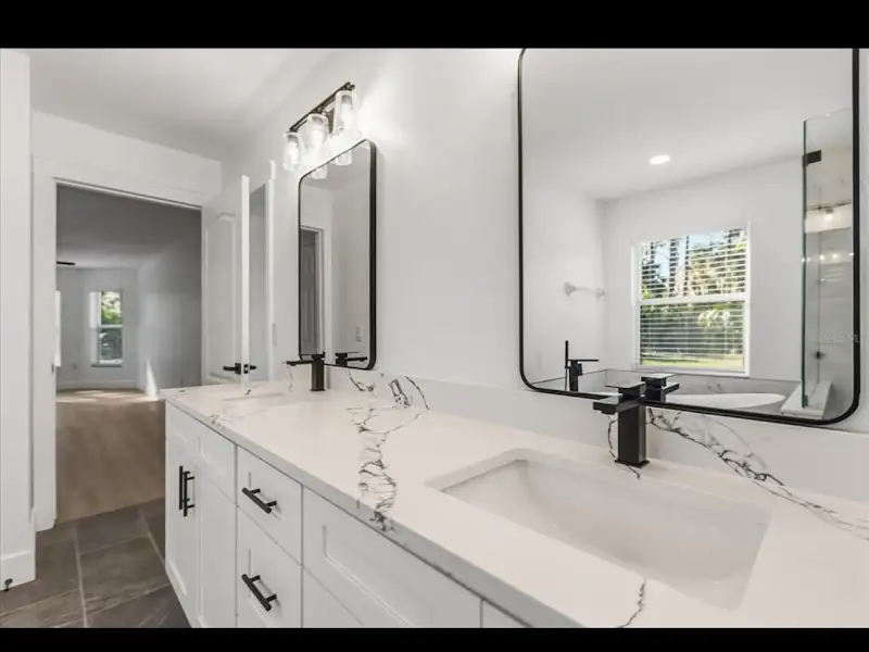 Double vanity with marble countertop and modern mirrors by JM Home Industries