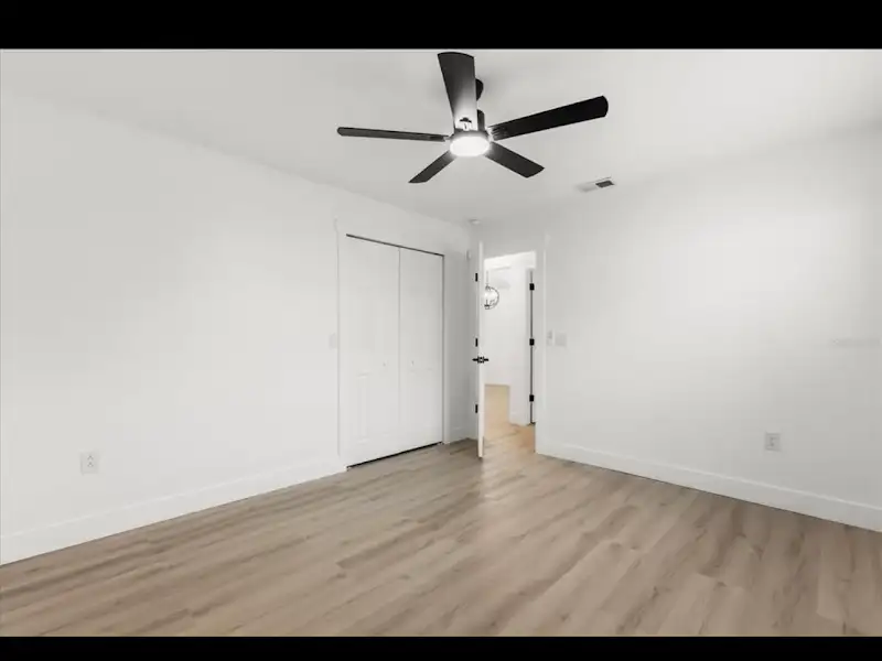 Bedroom with closet doors and hardwood by JM Home Industries