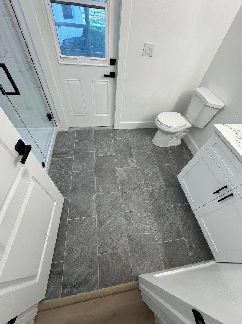 Bathroom remodel with dark tile flooring by JM Home Industries