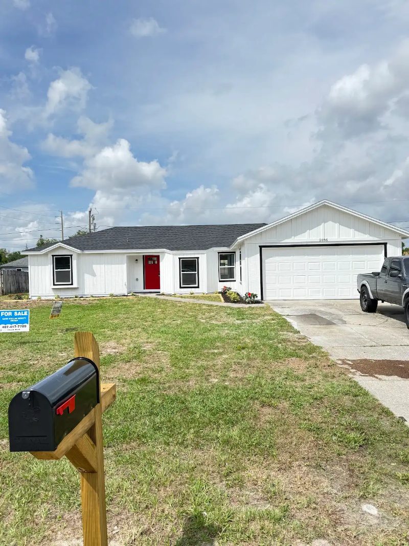 White home exterior with red door by JM Home Industries